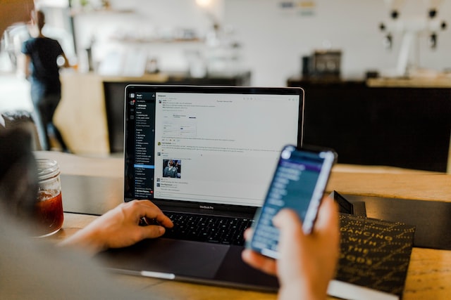 Person using their phone and laptop at the same time